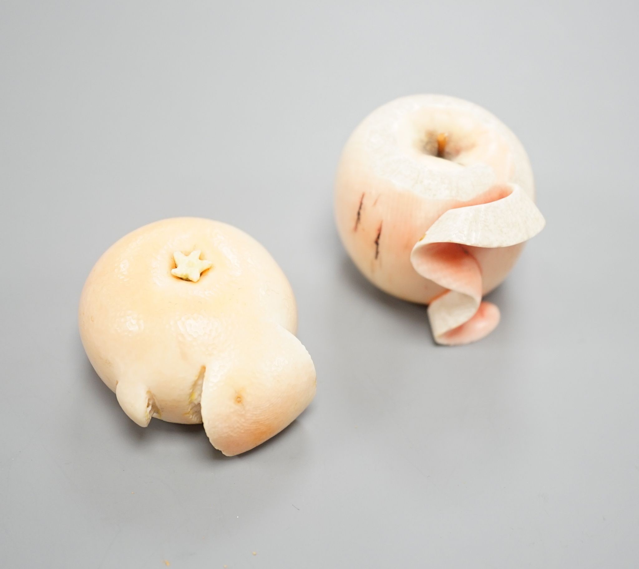 Two Japanese ivory models of a peeled apple and a satsuma, Meiji period, 3.5 cms high.